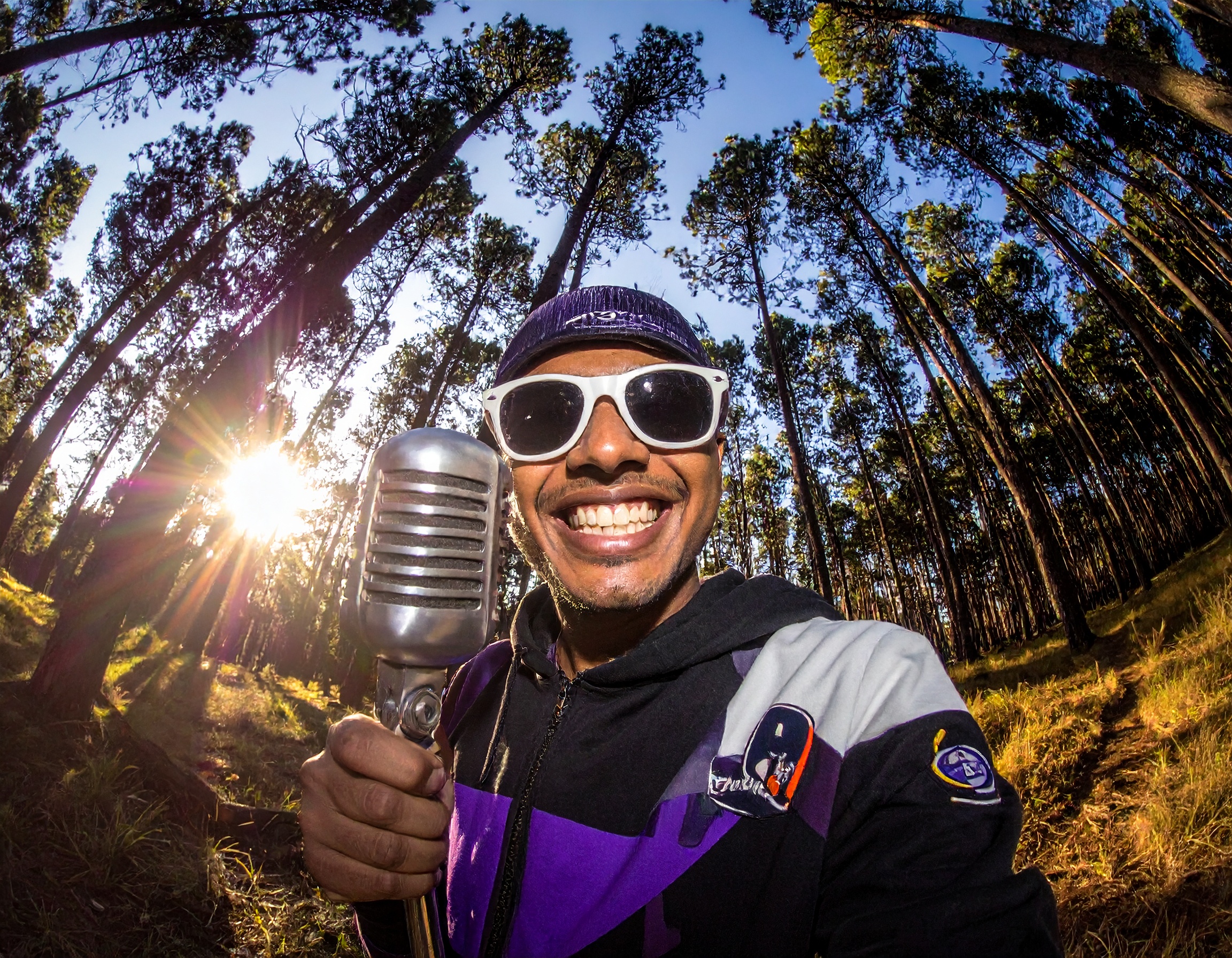 Man wearing sunglasses in a forest holding a branded product