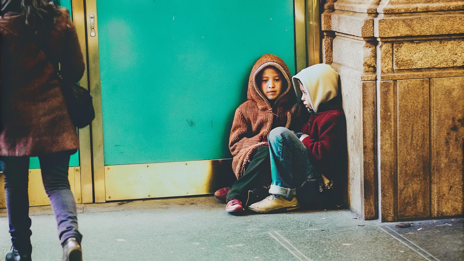Two children sitting by building entrance