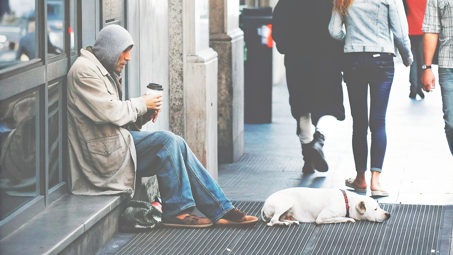 Man sitting with dog on city sidewalk