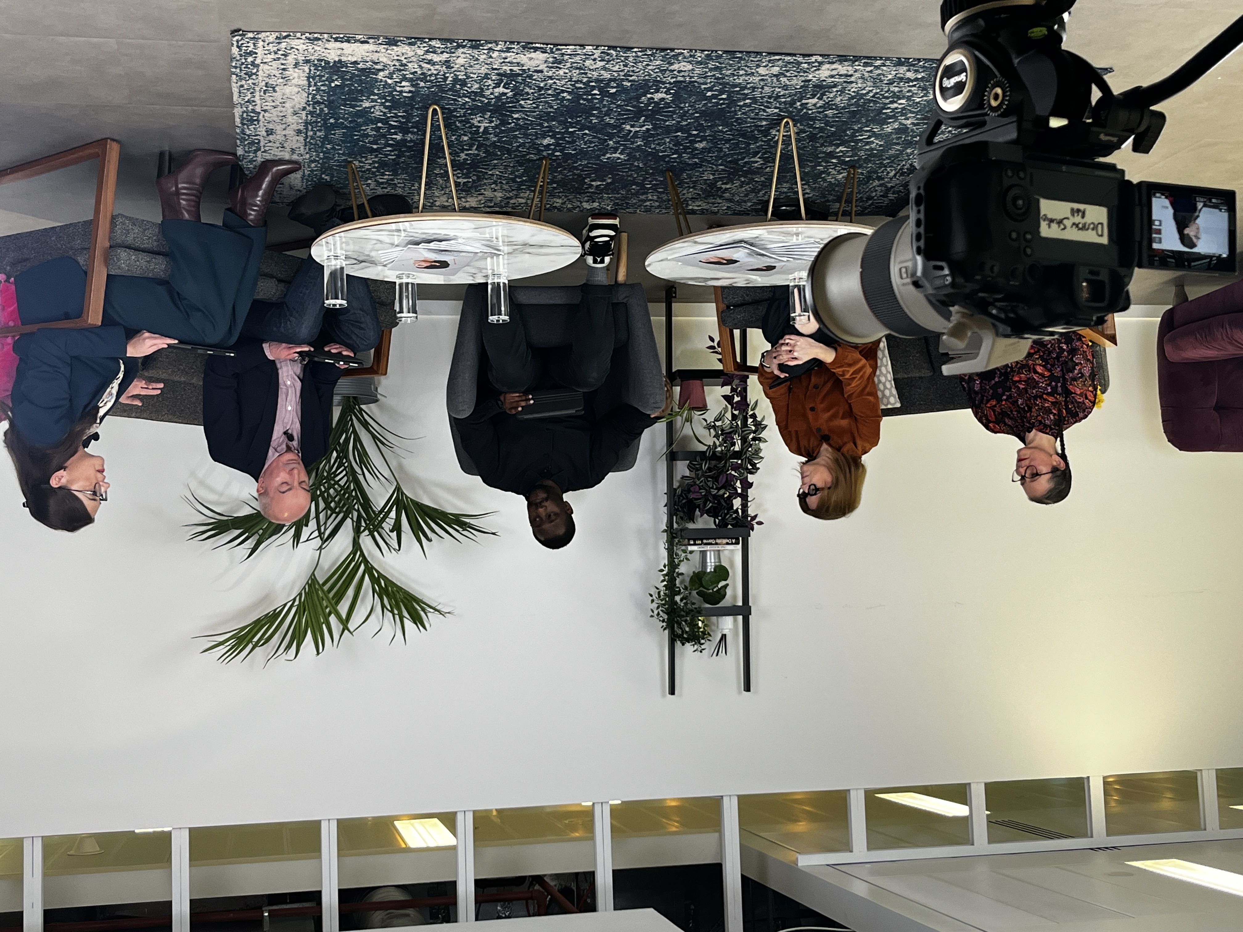 A panel of five people seated in a studio-style setting