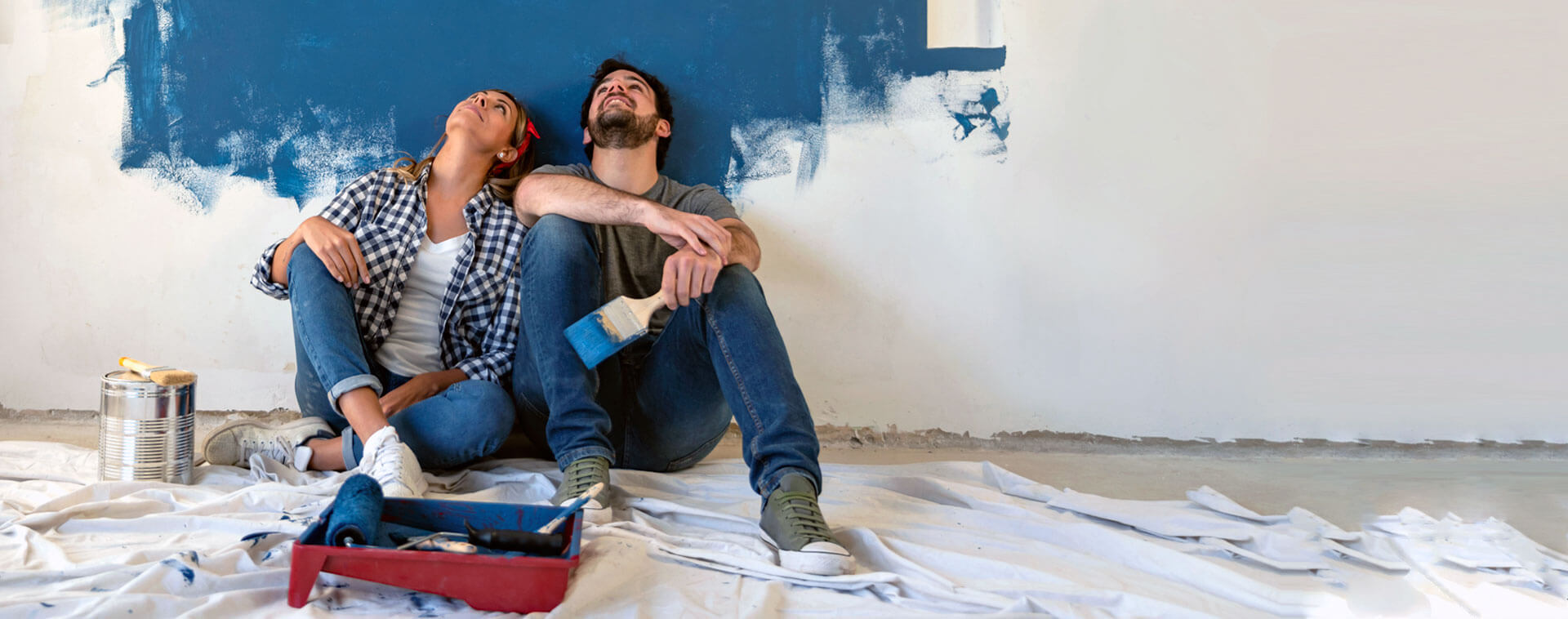 Dos personas pintando una pared de color azul