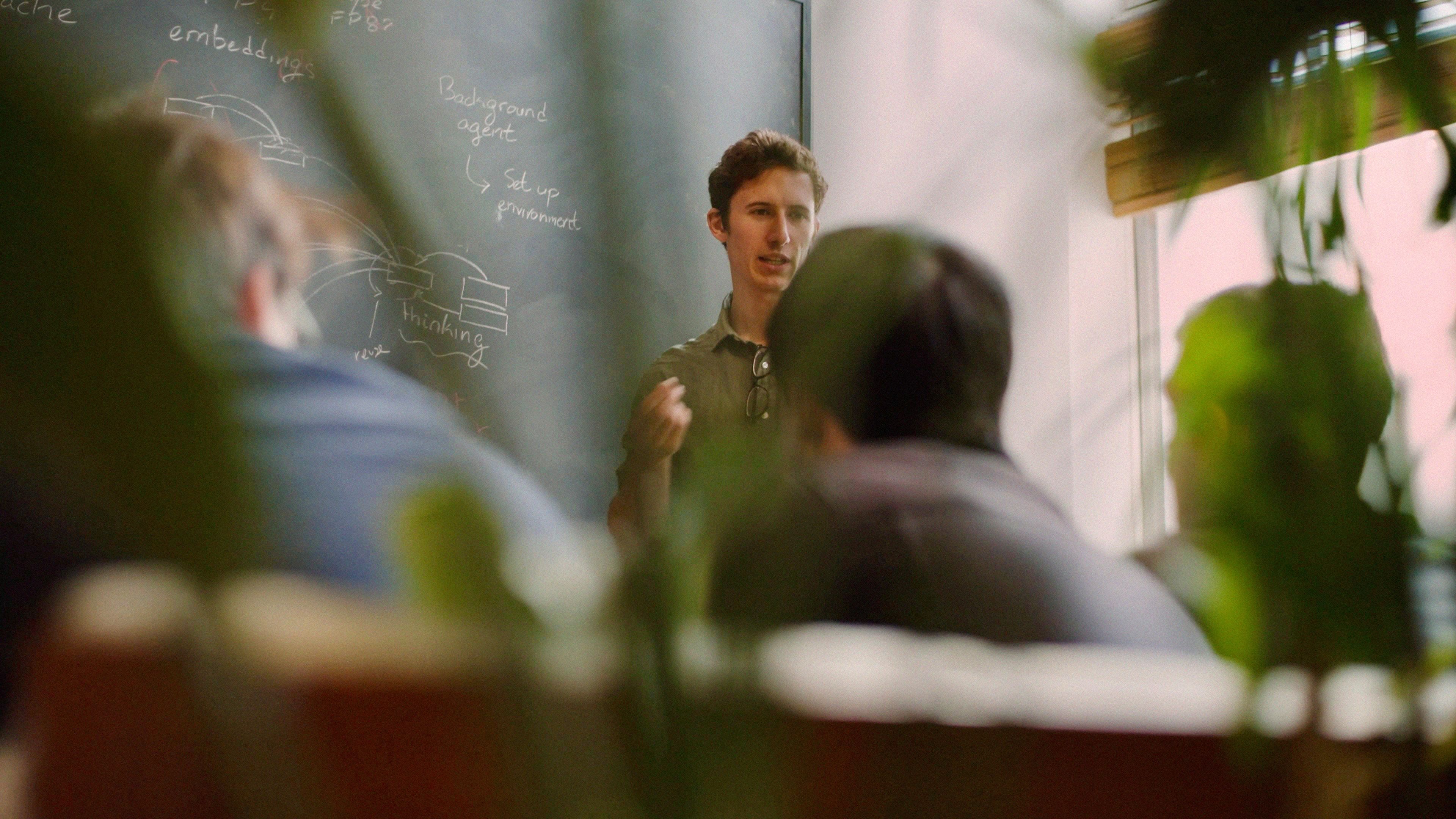 A photo of the Cursor team in an office environment, gathered around a whiteboard.