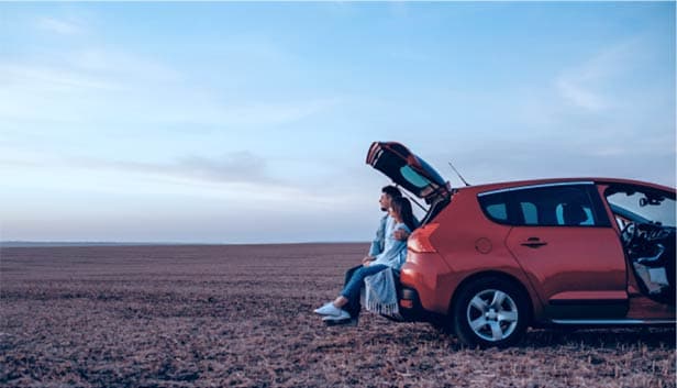 Person standing next to car in desert landscape representing savings and auto loan services