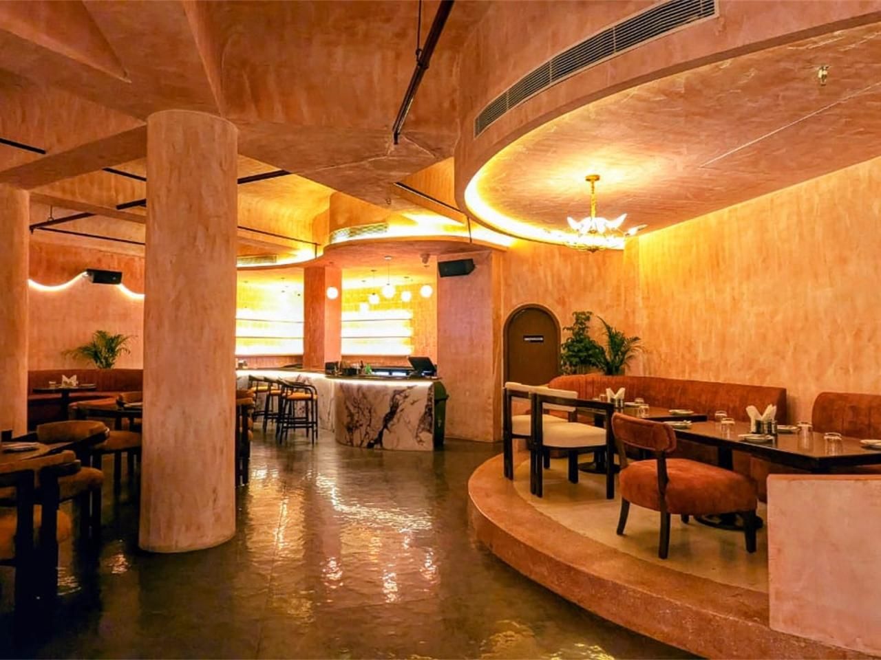 Elegant restaurant interior with warm terracotta walls, ambient cove lighting, and marble bar