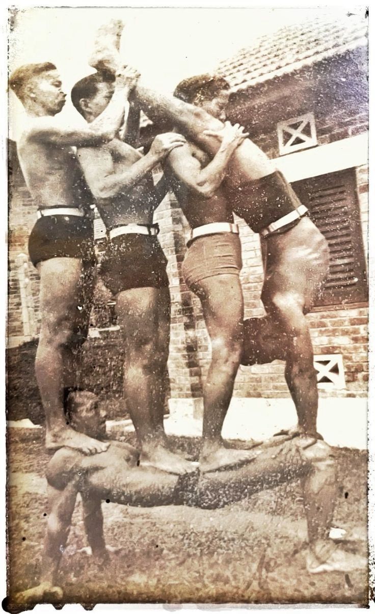 Vintage photograph of Ah Kong performing his signature strongman feat - lifting four bodybuilders in a reverse pushup